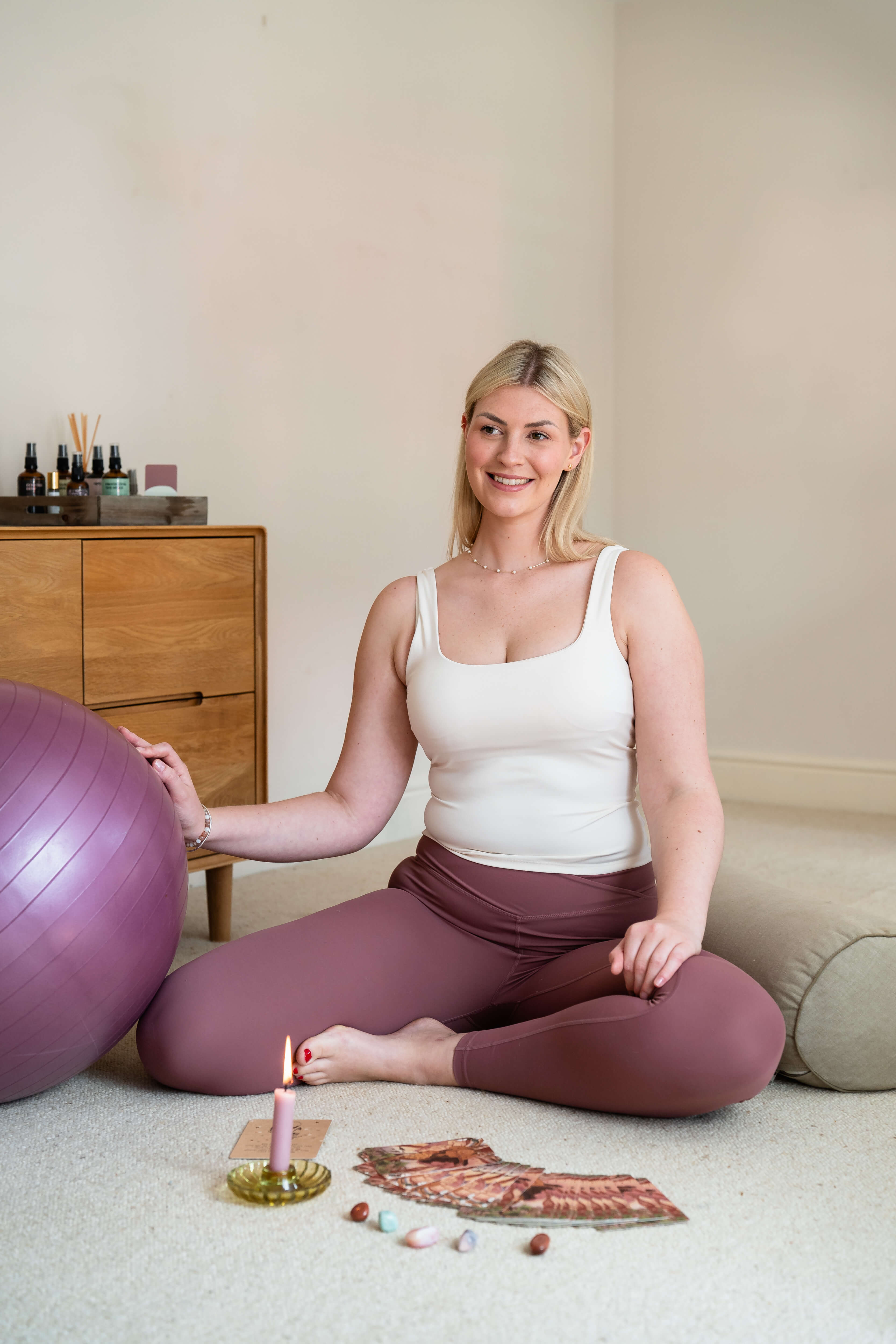 Rosie in a yoga position with cards, crystals, and a candle in front of her.